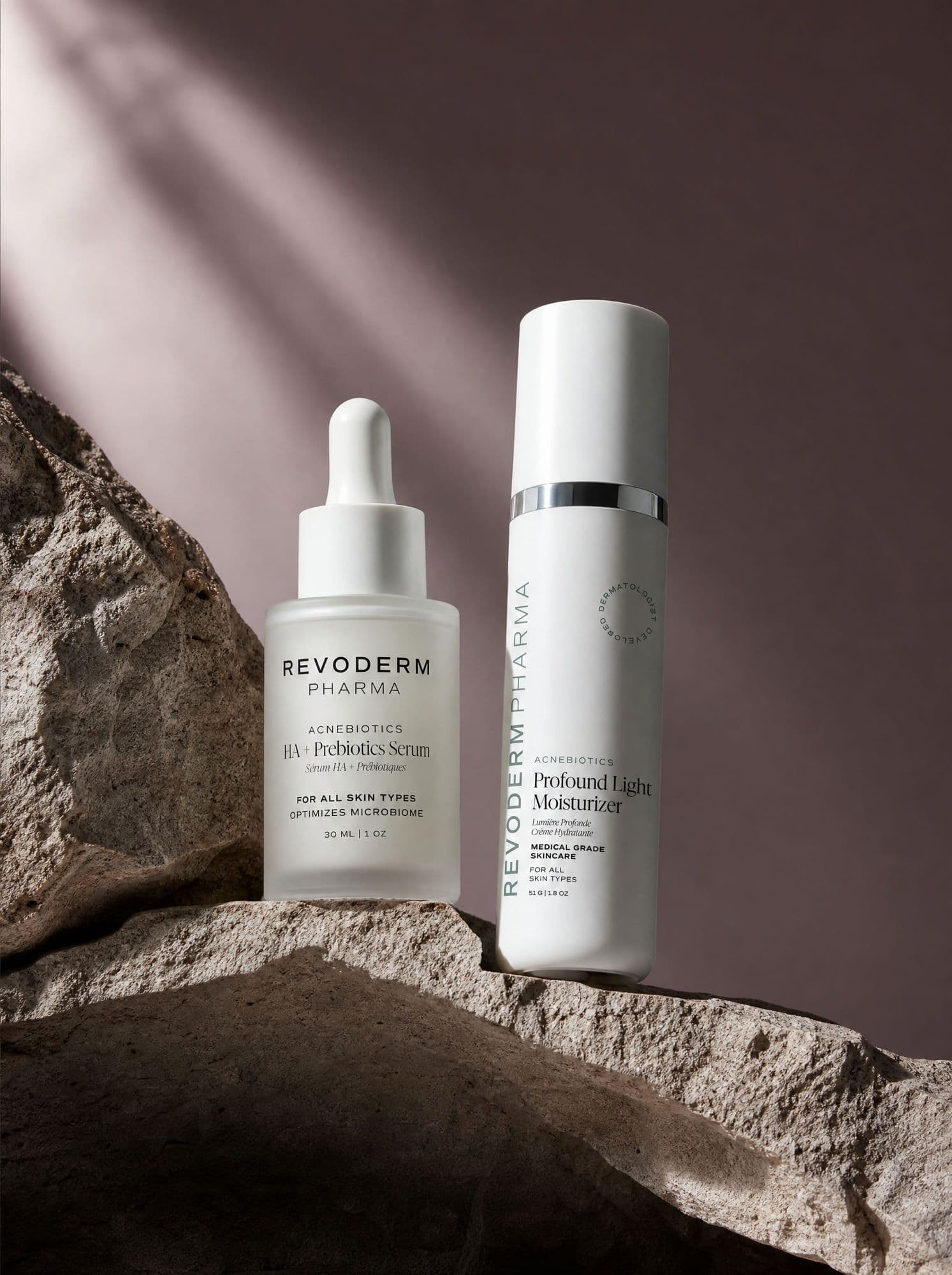 Prebiotic serum and moisturizer bottles staged on sunlit stone