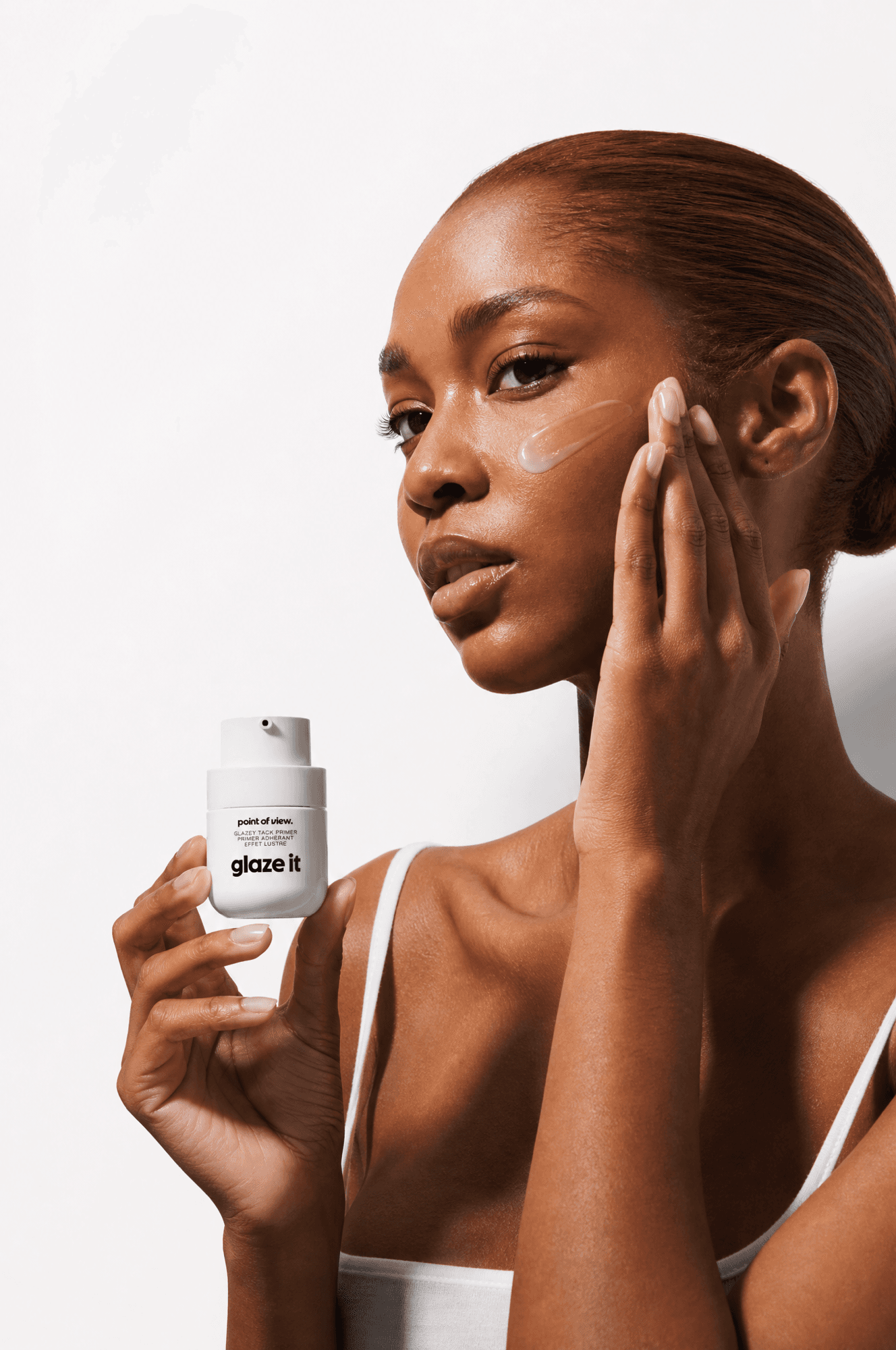 Woman applying a glossy skin primer dot to her cheekbone