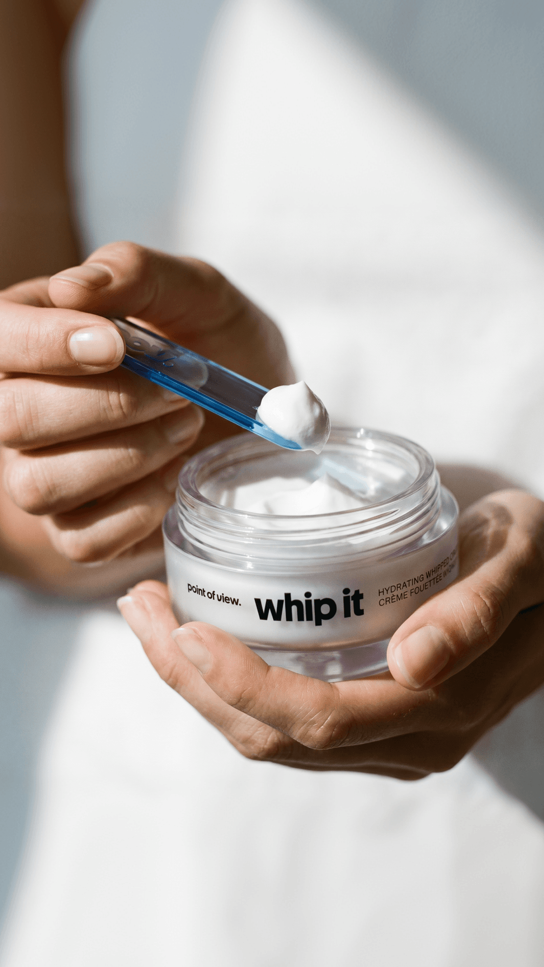 Hands scooping hydrating whipped face cream from an open jar