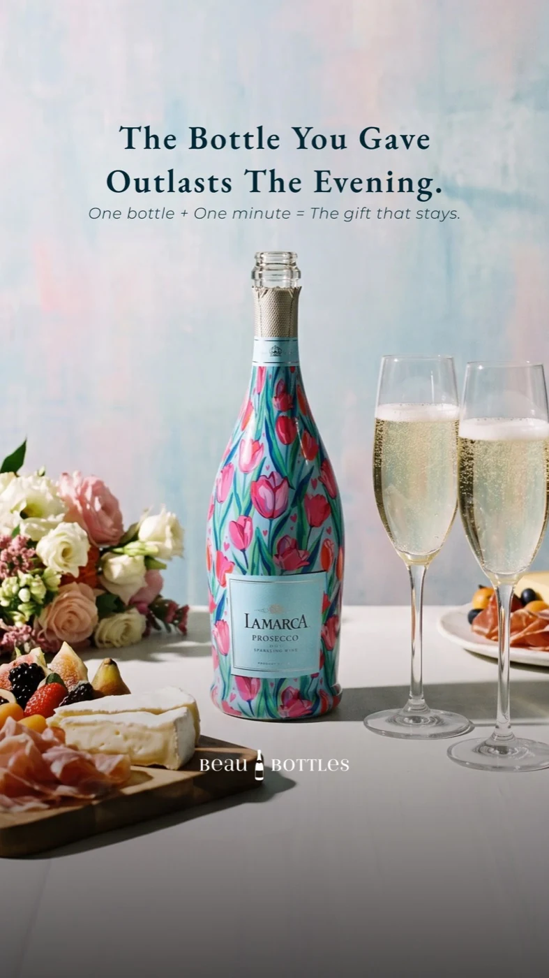 A floral Beau Bottles champagne gift beside glasses on a table