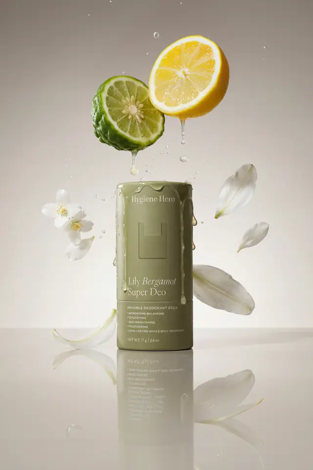 Hygiene Hero Lily Bergamot deodorant with lime, lemon and lily petals in mid-air.