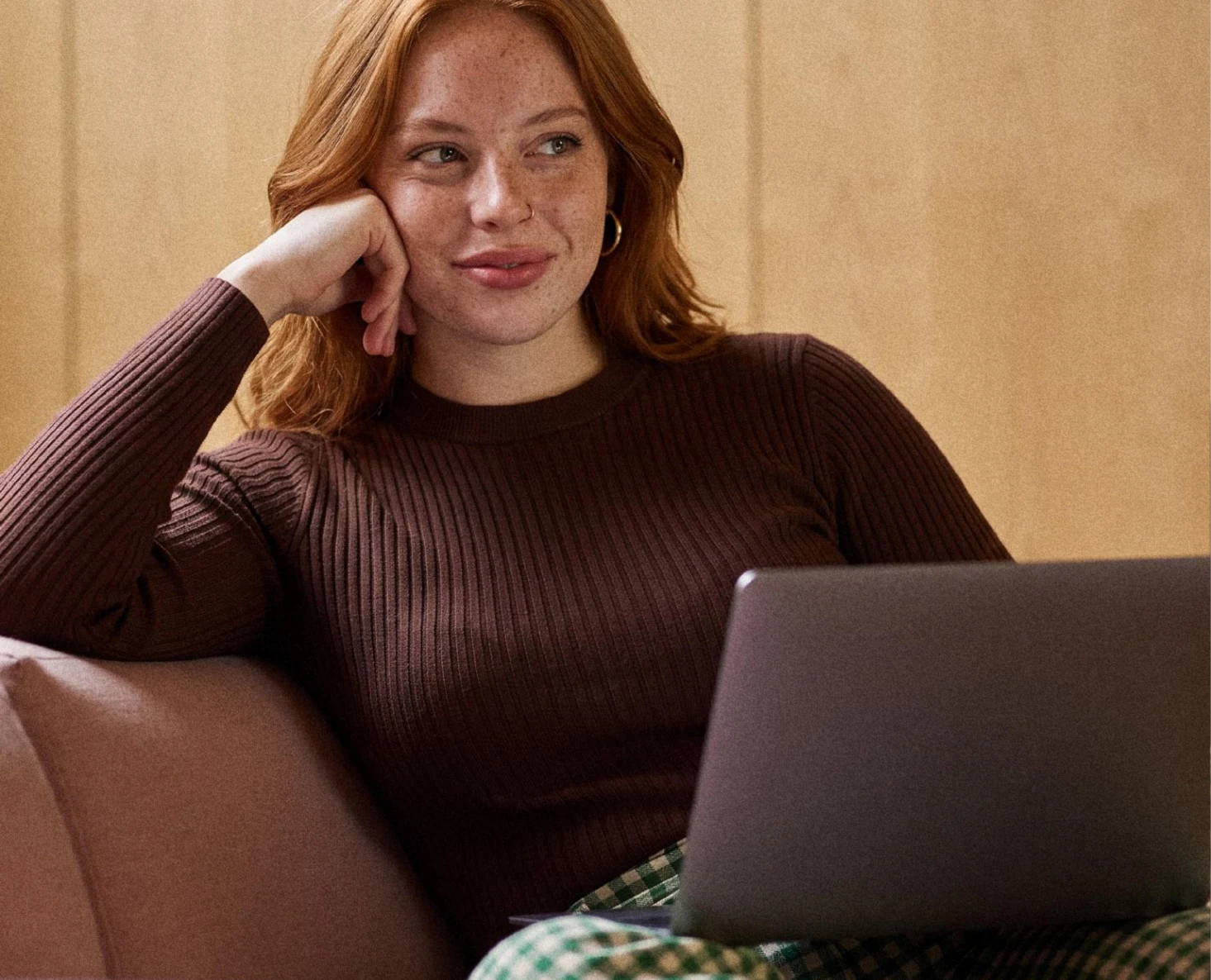 A woman working on a laptop in a warm, relaxed setting.