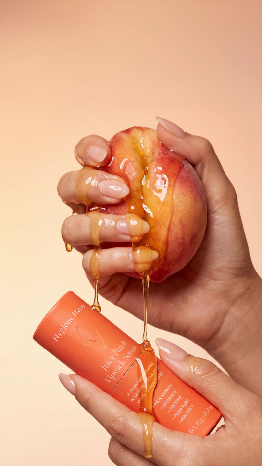 Orange skincare product squeezed into a hand against a peach background.