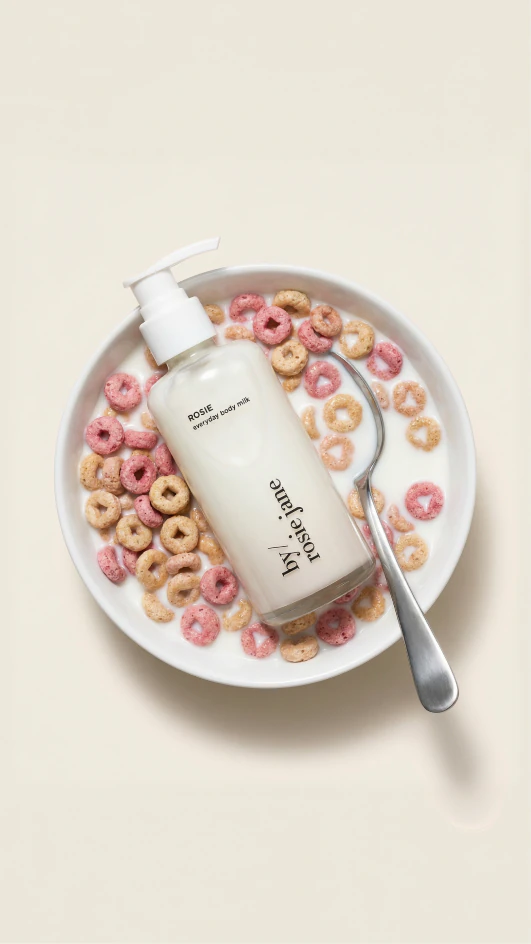 White skincare bottle arranged in a cereal bowl with a spoon.