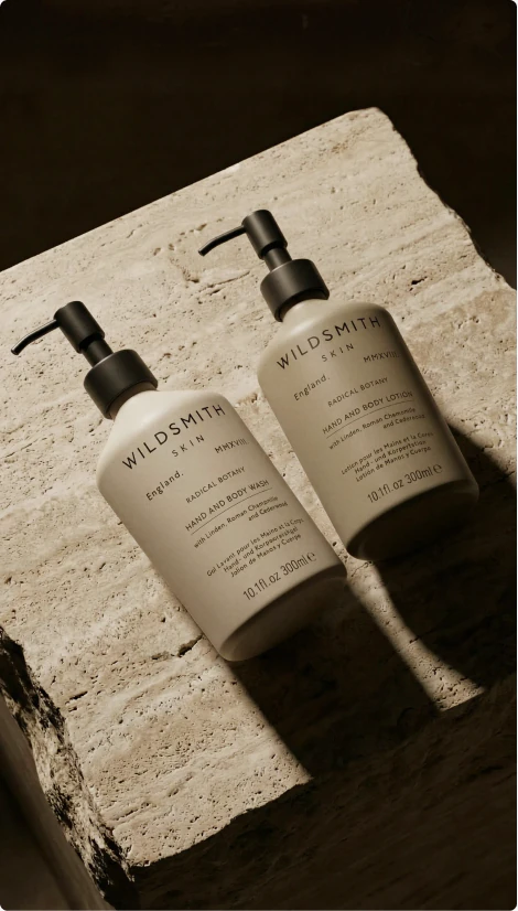 Two neutral skincare pump bottles on textured stone.