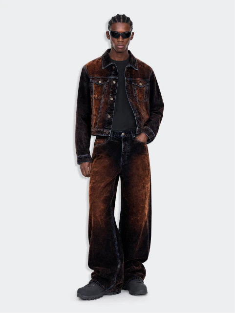 Fashion model in dark eyewear wearing a brown jacket and trousers.