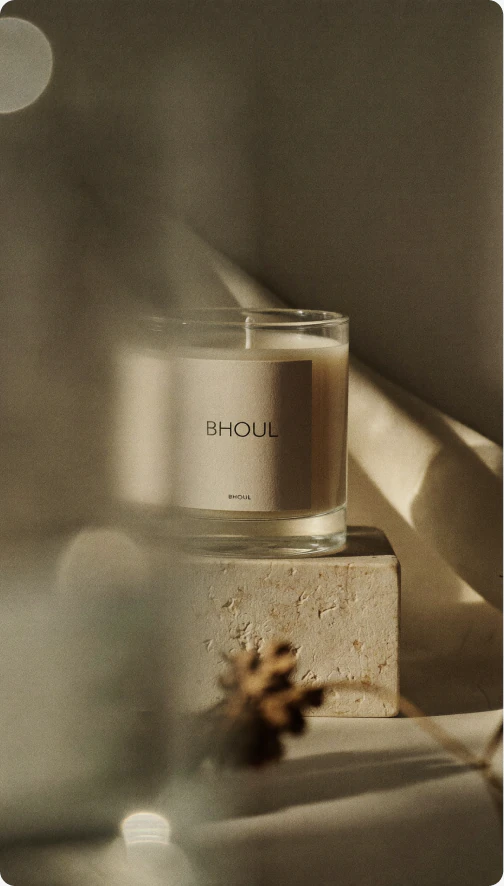 Bhouli candle in warm afternoon light beside dried flowers.