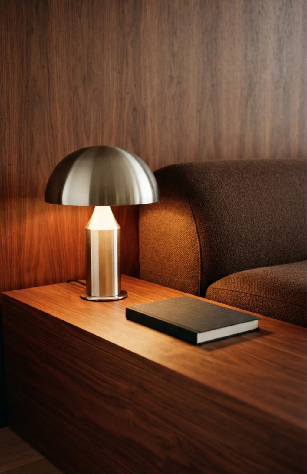Small metallic lamp glowing on a wooden bedside table.