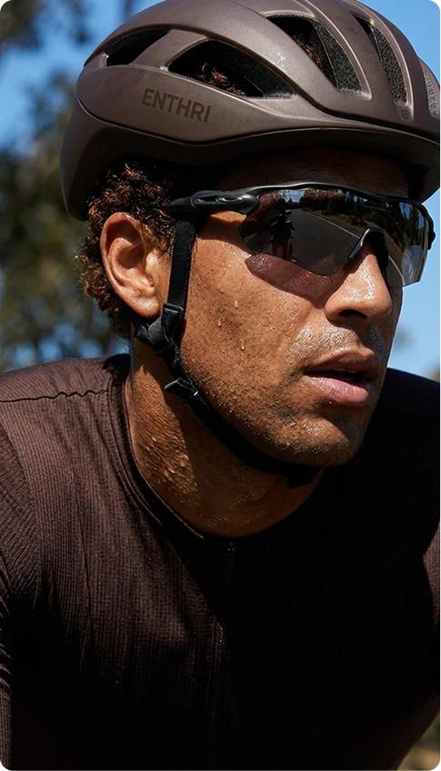 Cyclist in a black helmet and sports sunglasses outdoors.