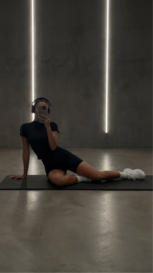 Woman seated in a dark gym between two vertical light strips.